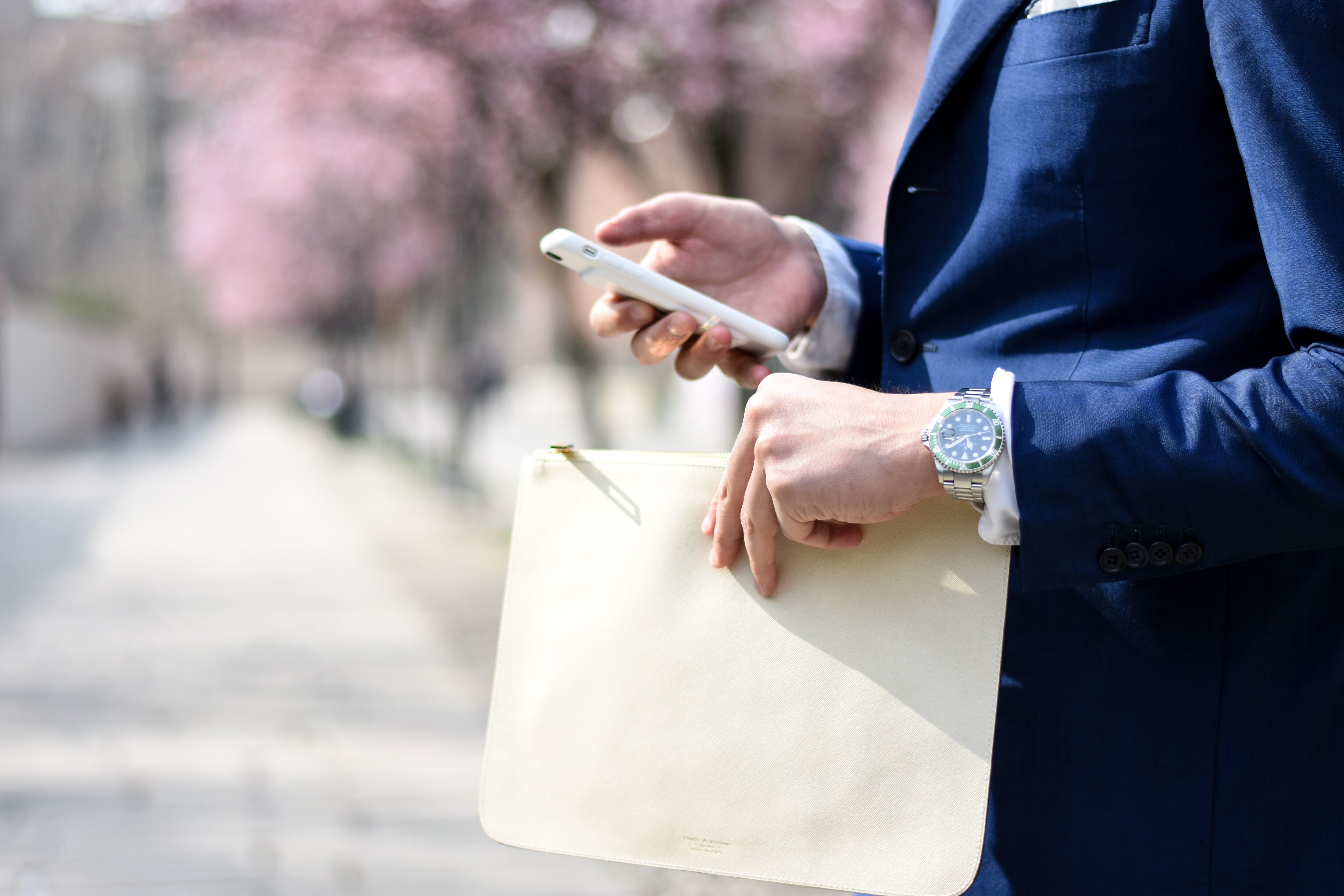 Man bär Rolex-klocka på handleden och mobil i handen